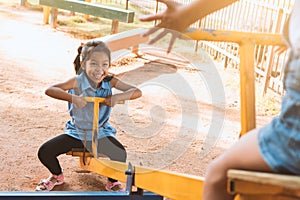 Two cute asian child girls playing seesaw together in the playground