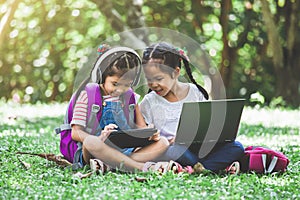 Two cute asian child girls using tablet and laptop