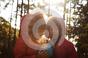 Two cute Asian girls learning a model of the world on nature background and warm sunlight in the park. Children learn through