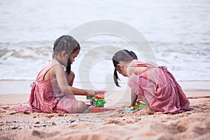 Two cute asian little child girls having fun to play with sand