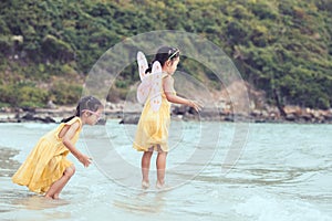 Two cute asian little child girls play and jump on beach