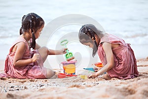 Two cute asian little child girls play with sand on beach