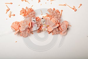 Two cute baby dolls sitting in front of artificial flowers garland
