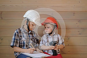 Two cute boys in construction helmets are discussing a plan for the upcoming work. children play builders