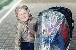 Two cute caucasian siblings in casual sport clothes having fun enjoy walking during rain in autumn day. Sister with