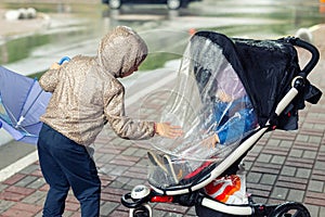 Two cute caucasian siblings in casual sport clothes having fun enjoy walking during rain in autumn day. Sister with