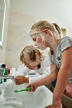 Two cute children, boy and girl rinsing mouth after brushing teeth in the morning