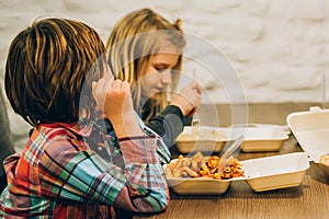 Two cute children eats spaghetti pasta in fast food restaurant photo