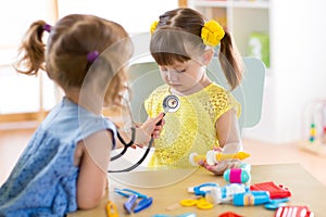 Two cute children playing doctor and hospital using stethoscope. Friends girls having fun at home or preschool.