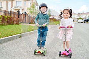Two Cute Children Riding Scooters
