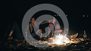 Two cute couples embracing each other and sitting by the bonfire late at night looking at the stars