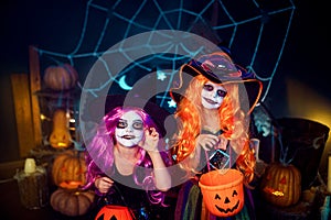 Two cute funny sisters celebrate the holiday. Jolly children in carnival costumes ready for Halloween.