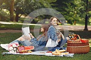 Two cute girls in a park playing with little dog