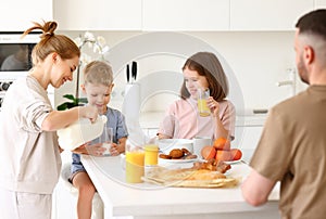 Two cute happy kids waiting for morning meal in kitchen