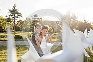 Two cute kids cuddle in the backyard of the house. Brother and sister near the white wind turbines. A boy and a girl have fun on a photo