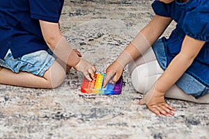 Two cute kids playing with flexible toy the Pop It fidget.