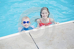 Two cute kids playing in a swimming pool on a sunny day