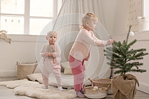 Two cute little baby girls play in a spacious bright minimalistic children`s room.