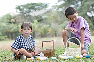 Two cute little Caucasian and Asian child boy hunting Easter eggs. kids collecting eggs in basket, counting eggs after play game