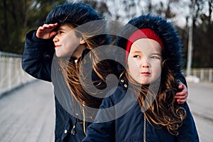 Two cute little children hugging in autumn park. Close up lifestyle fashion portrait of two beautiful caucasian girls outdoors, we