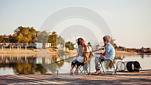 Two cute little friends, boy and girl fishing on a lake in a sunny summer day