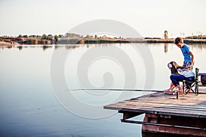 Two cute little friends, boy and girl fishing on a lake in a sunny summer day