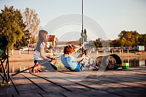 Two cute little friends, boy and girl fishing on a lake in a sunny summer day