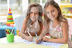 Two cute little girls drawing with pencils