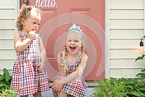 Two cute little girls eating frozen fruit pops in summer