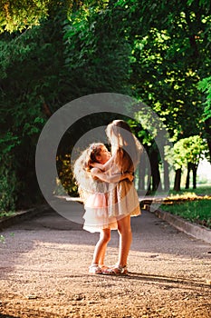 Two Cute little girls hugging and laughing at the garden at warm summer evening. Happy kids outdoors concept. Soft focused