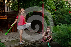 Two cute little girls playing with a city fountain on hot and sunny summer day. Two little girls in the summer