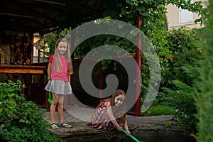 Two cute little girls playing with a city fountain on hot and sunny summer day. Two little girls in the summer