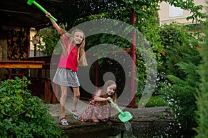 Two cute little girls playing with a city fountain on hot and sunny summer day. Two little girls in the summer