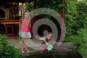 Two cute little girls playing with a city fountain on hot and sunny summer day. Two little girls in the summer