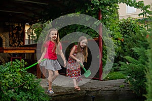 Two cute little girls playing with a city fountain on hot and sunny summer day. Two little girls in the summer