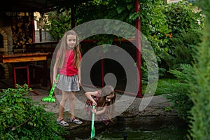 Two cute little girls playing with a city fountain on hot and sunny summer day. Two little girls in the summer