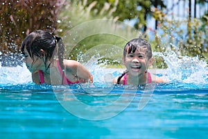 Two cute little girls playing in the pool. Summer lifestyle concept