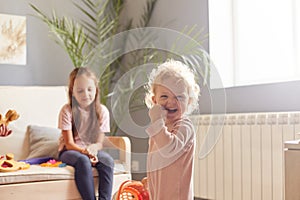 Two cute little girls sisters playing with toys in living room together, preschool kids enjoying playtime, having fun at home