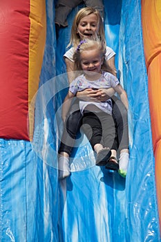 Two Cute Little Girls Sliding Down Blowup Slide photo