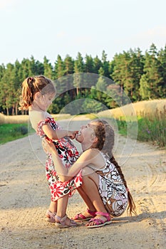 Two Cute  little girls smiling and playing at the field in warm summer day. Happy childhood concept