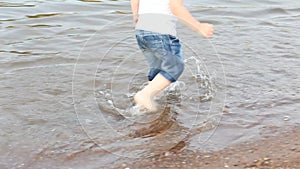 Two cute little kids boys playing, walking on the water on a beach. Summer water fun.