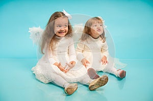 Two cute little sisters with angel's wings