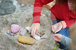 Two cute little sisters collecting beautiful stones on a pebble beach