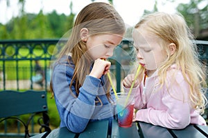 Two cute little sisters drinking frozen slushie drink