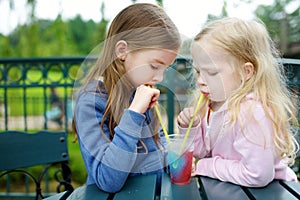 Two cute little sisters drinking frozen slushie drink photo