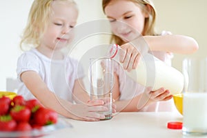 Two cute little sisters eating cereal in a kitchen