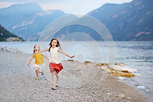 Two cute little sisters having fun on a beach of Limone sul Garda, a small town and comune in the province of Brescia, Italy