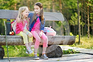 Two cute little sisters having fun during forest hike on beautiful summer day