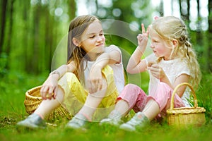 Two cute little sisters having fun during forest hike on beautiful summer day. Active family leisure with kids.