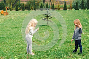 Two cute little sisters having fun in garden. Happy kids playing outdoors. Nature and outdoors fun for family. Happy and healthy